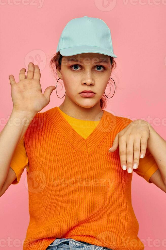 bonito niña en un naranja suéter en azul tapas mano gesto recortado ver inalterado foto
