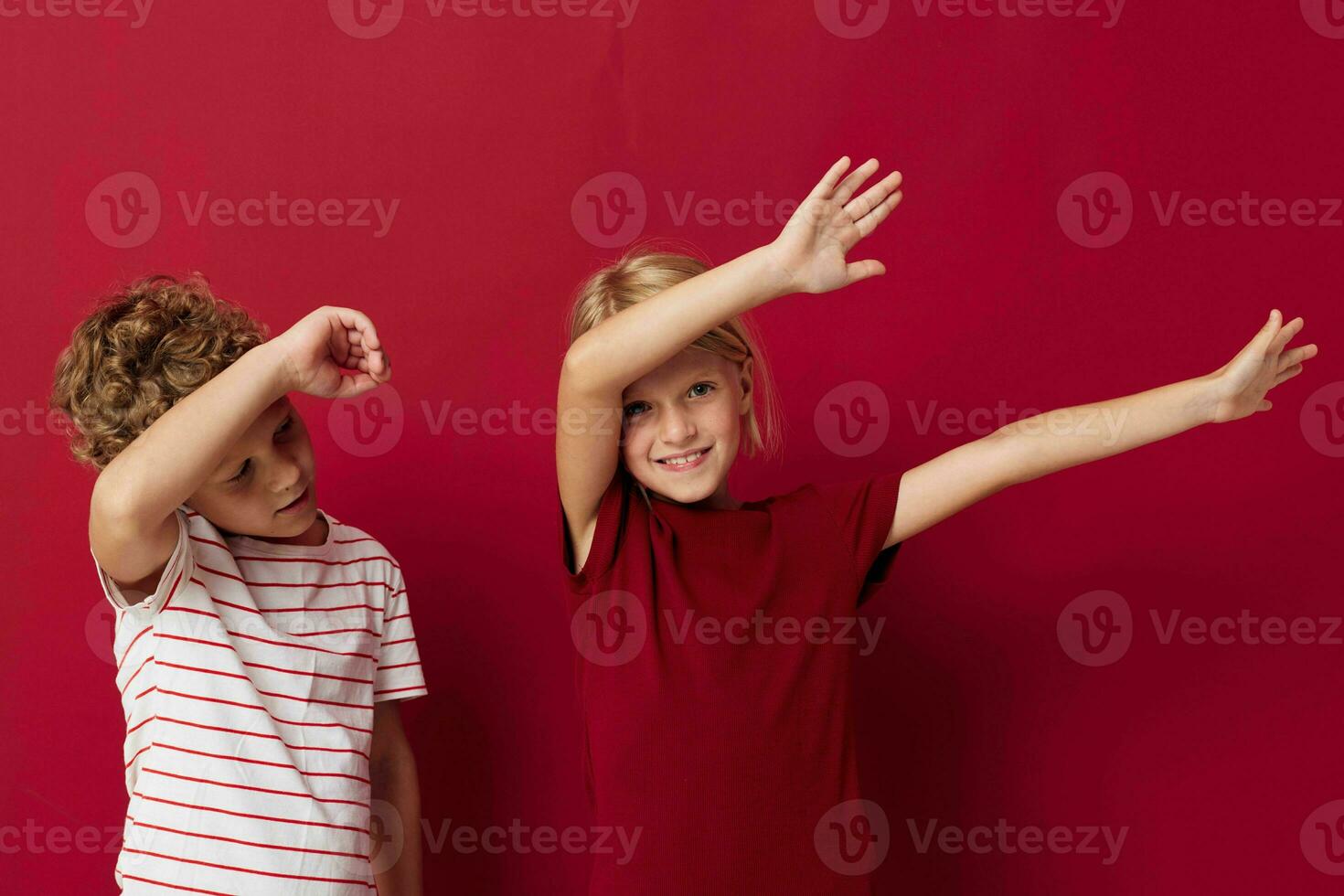 Small children good mood standing next to posing red background photo