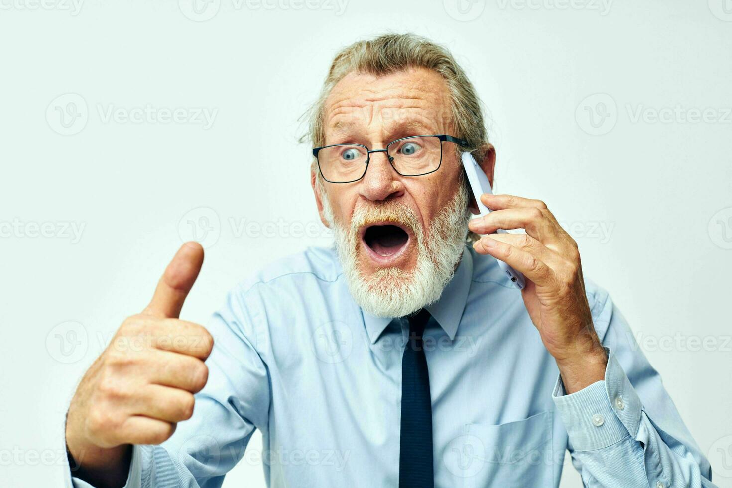 old man with phone in studio on white background shows thumb up photo