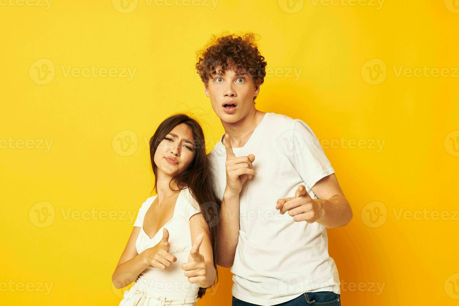 young boy and girl standing side by side in white t-shirts posing yellow background unaltered photo