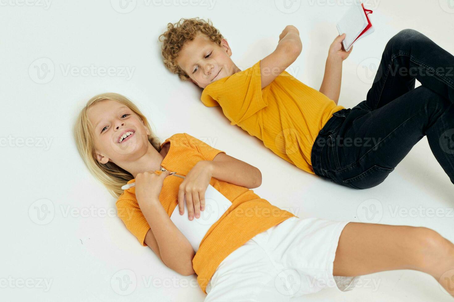 Cute preschool kids drawing in notebooks lying on the floor isolated background unaltered photo