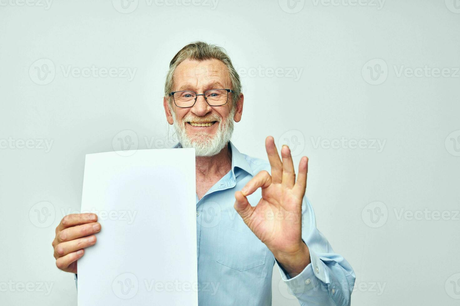 Portrait elderly man holding a sheet of paper copy-space posing cropped view photo