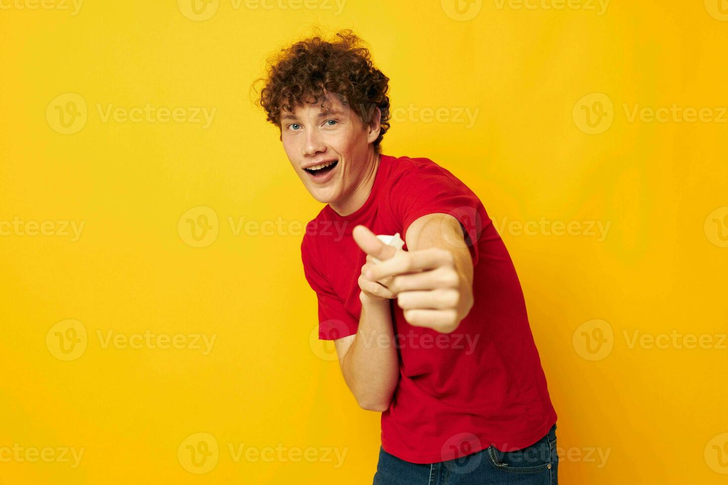 Young curly-haired man wearing a red t-shirt medical mask on the face posing isolated background unaltered photo