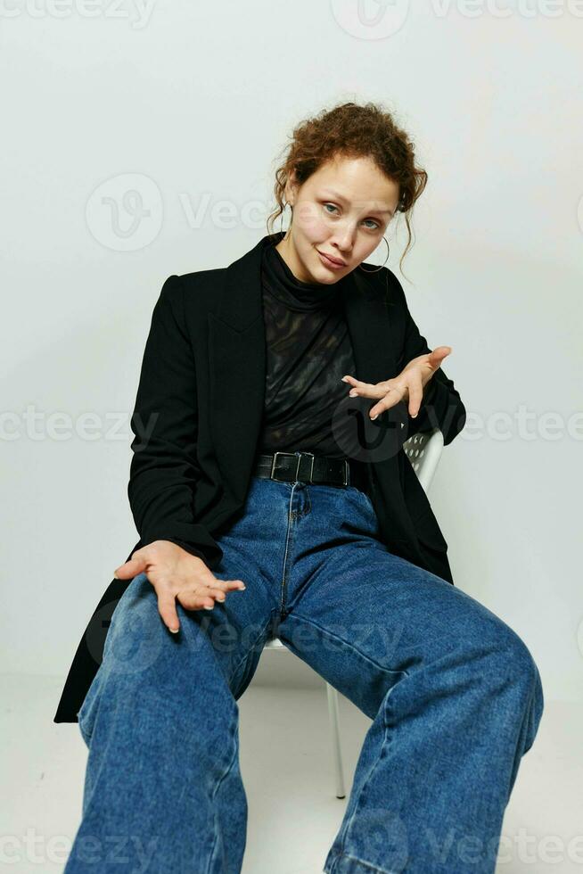 cheerful woman sitting on a chair in a black jacket fashion posing light background unaltered photo