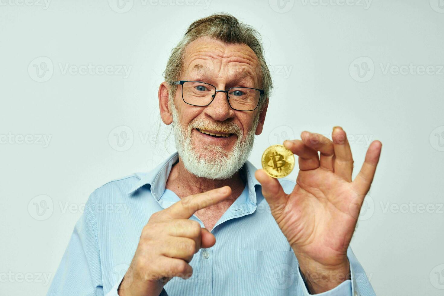 Photo of retired old man in blue shirts bitcoin in hands light background