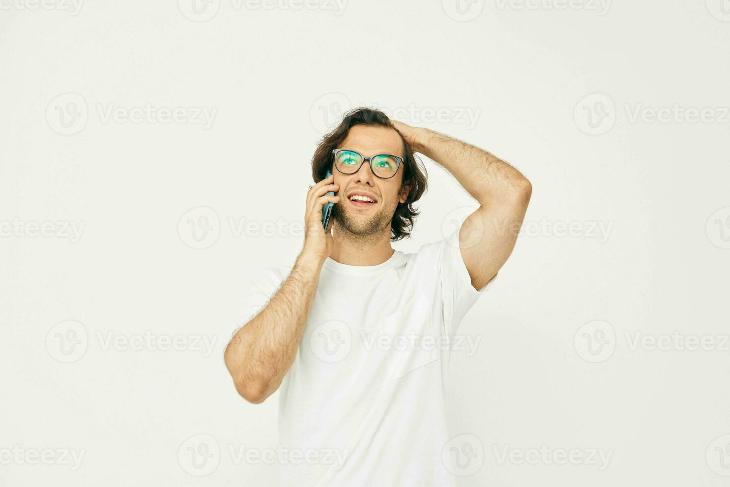 Attractive man in a white T-shirt communication by phone light background photo