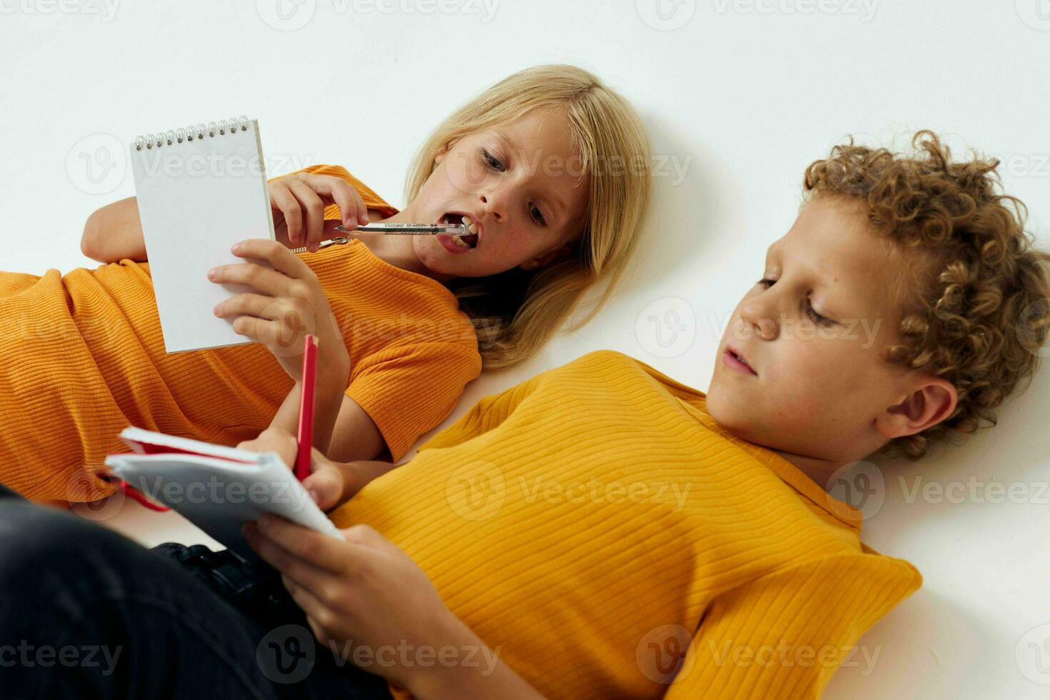 cheerful children lie on the floor with notepads and pencils childhood lifestyle unaltered photo