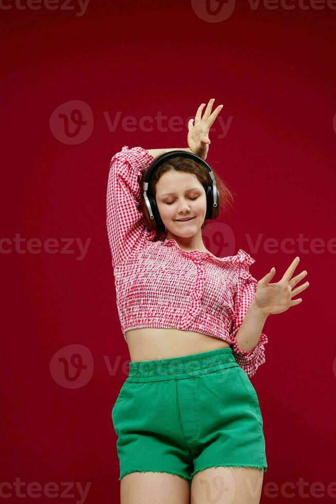 cheerful woman in green shorts listening to music on headphones photo