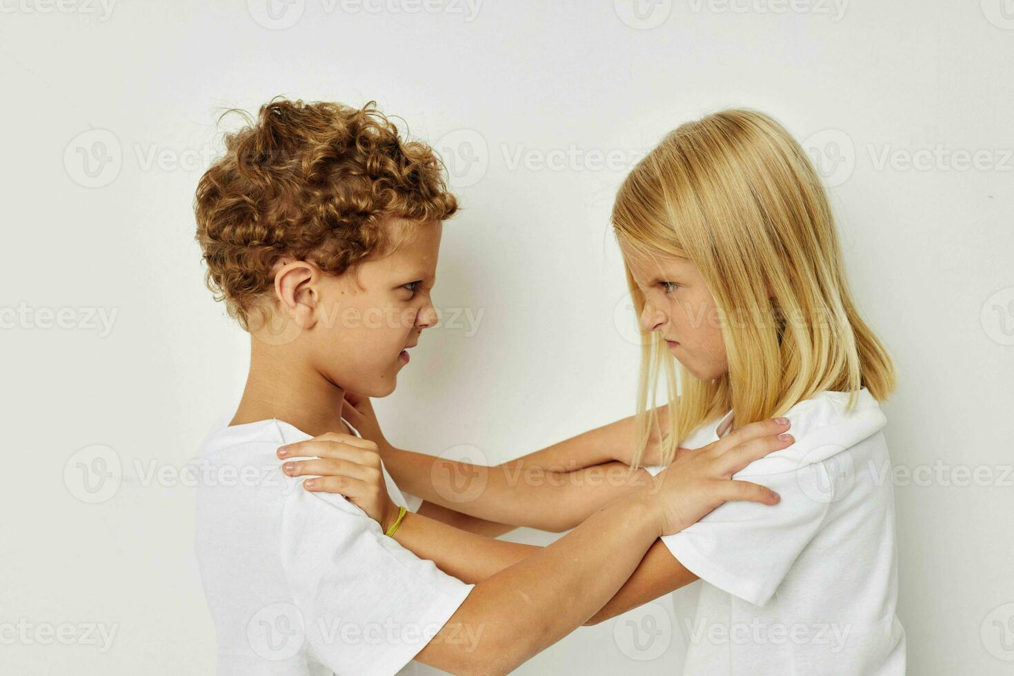 Photo of two children in white T-shirts are standing next to beige background