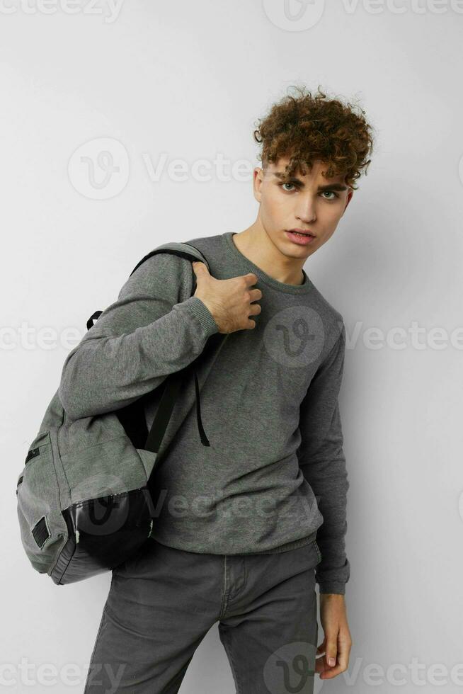 kinky guy in a gray sweater backpack fashion light background photo