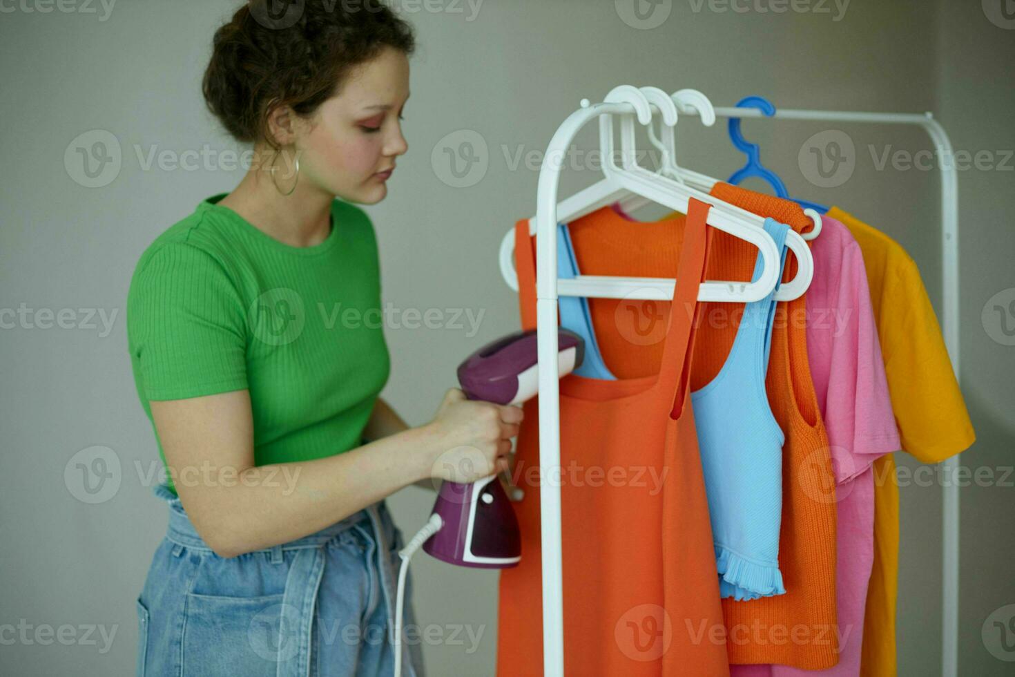 cheerful woman ironing clothes on a hanger wardrobe isolated backgrounds unaltered photo