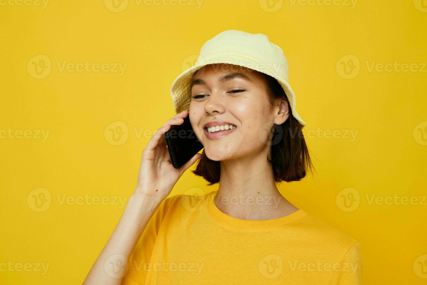 optimista joven mujer amarillo camiseta y sombrero verano estilo con teléfono estilo de vida inalterado foto