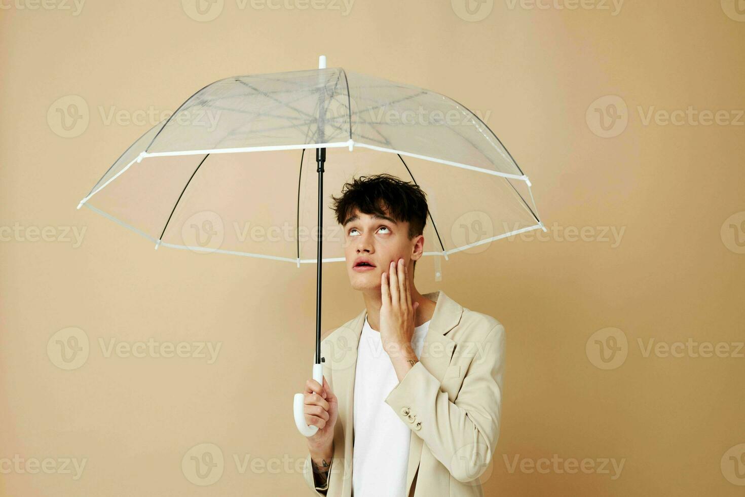 a man with an open umbrella in a jacket protection from the rain beige background photo