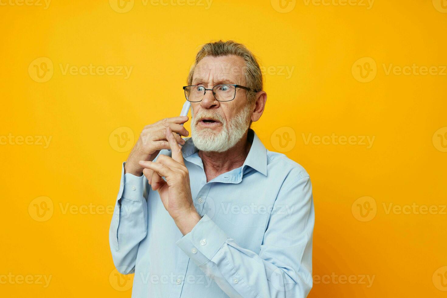 foto de retirado antiguo hombre en un azul camisa y lentes hablando en el teléfono amarillo antecedentes