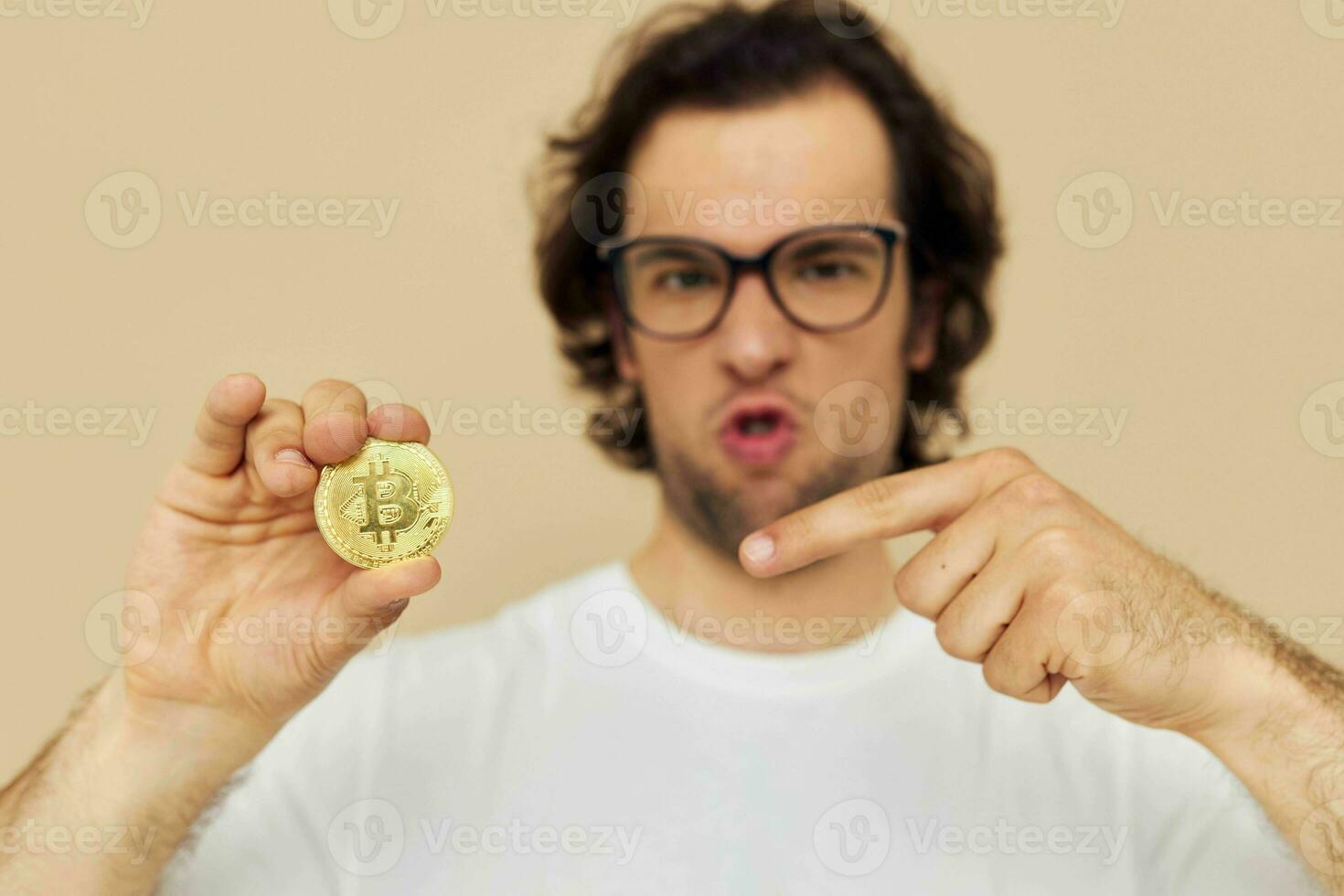 Attractive man in a white T-shirt with Bitcoin cryptocurrency beige background photo
