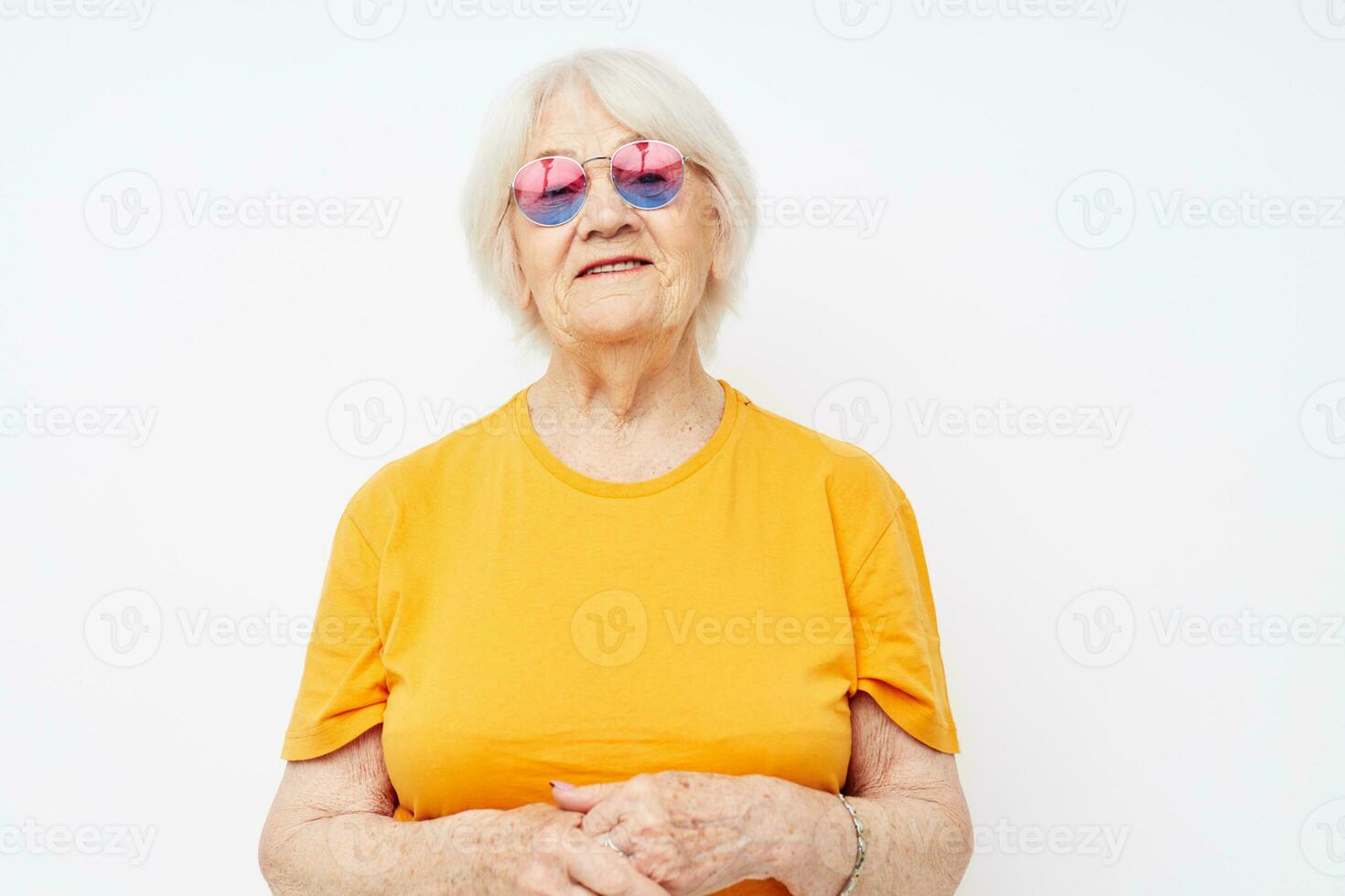 sonriente mayor mujer en un amarillo camiseta posando ligero antecedentes foto