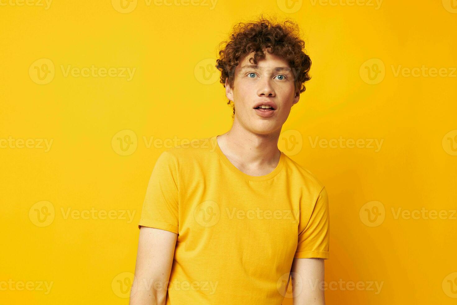 Young curly-haired man wearing stylish yellow t-shirt posing Lifestyle unaltered photo