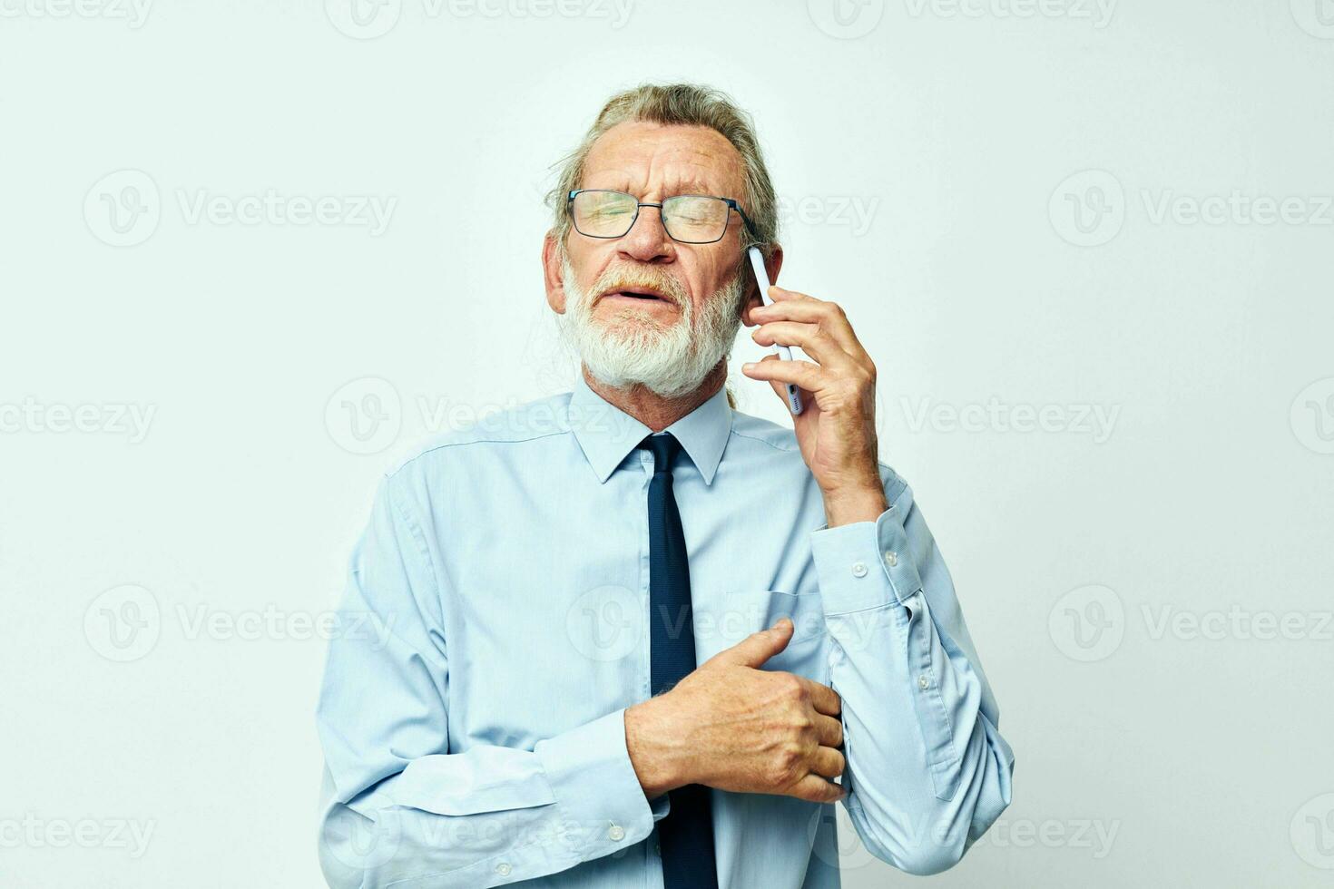 old man in glasses with a phone in the studio on a white background talking photo