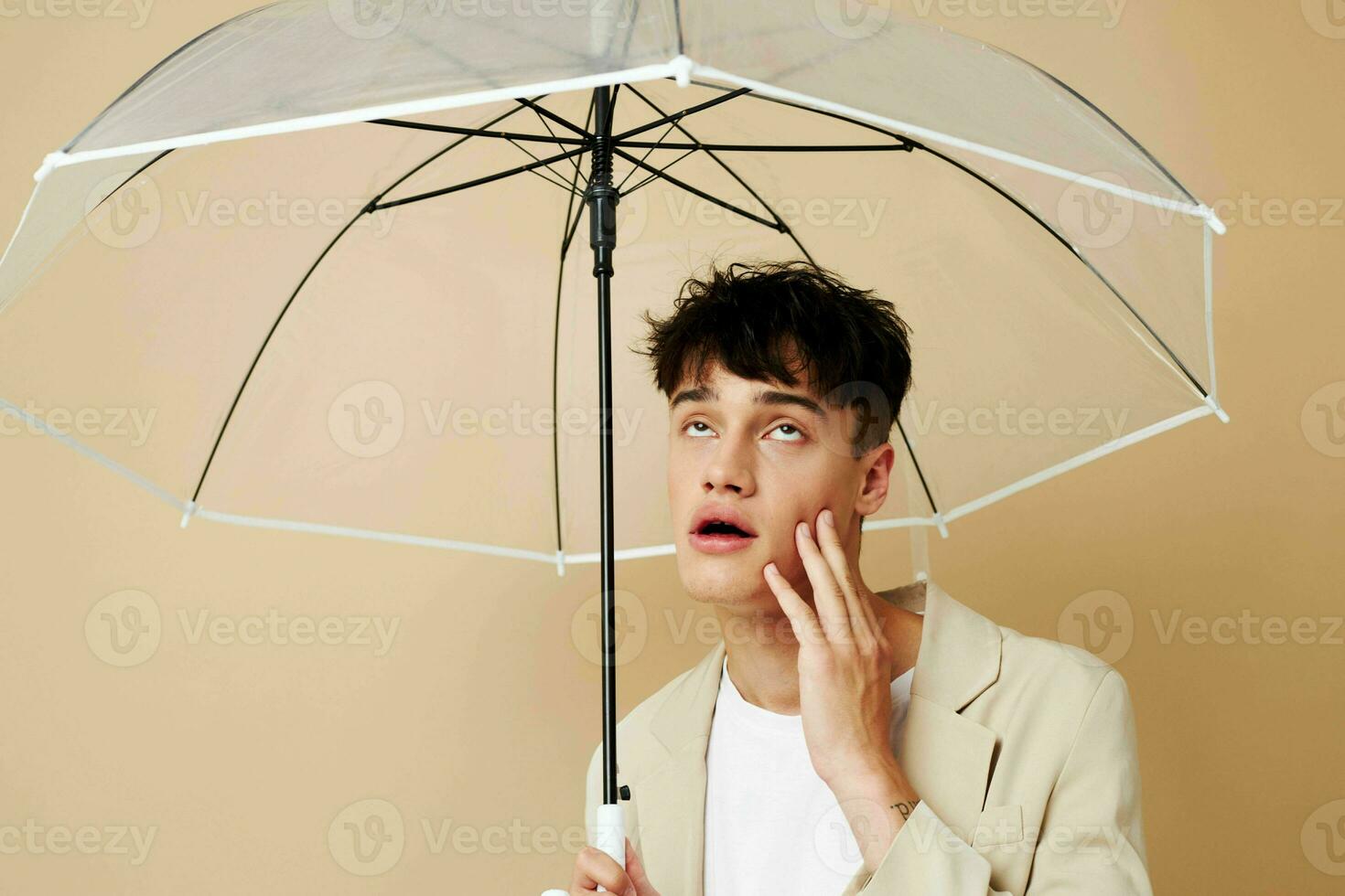 a man with an open umbrella in a jacket protection from the rain beige background photo
