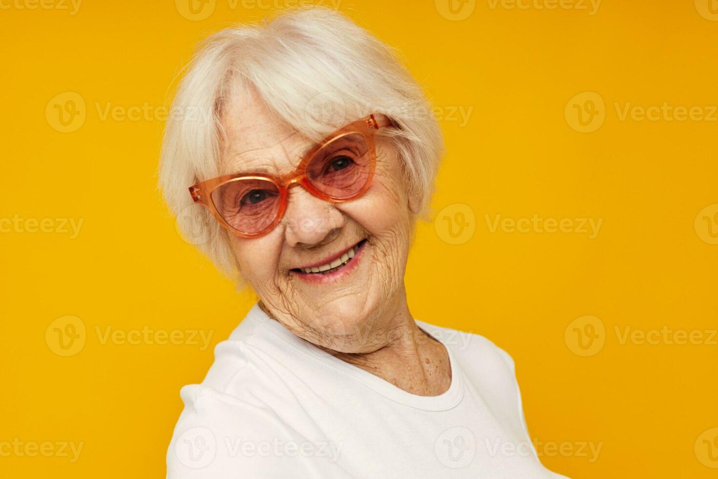 smiling elderly woman vision problems with glasses yellow background photo