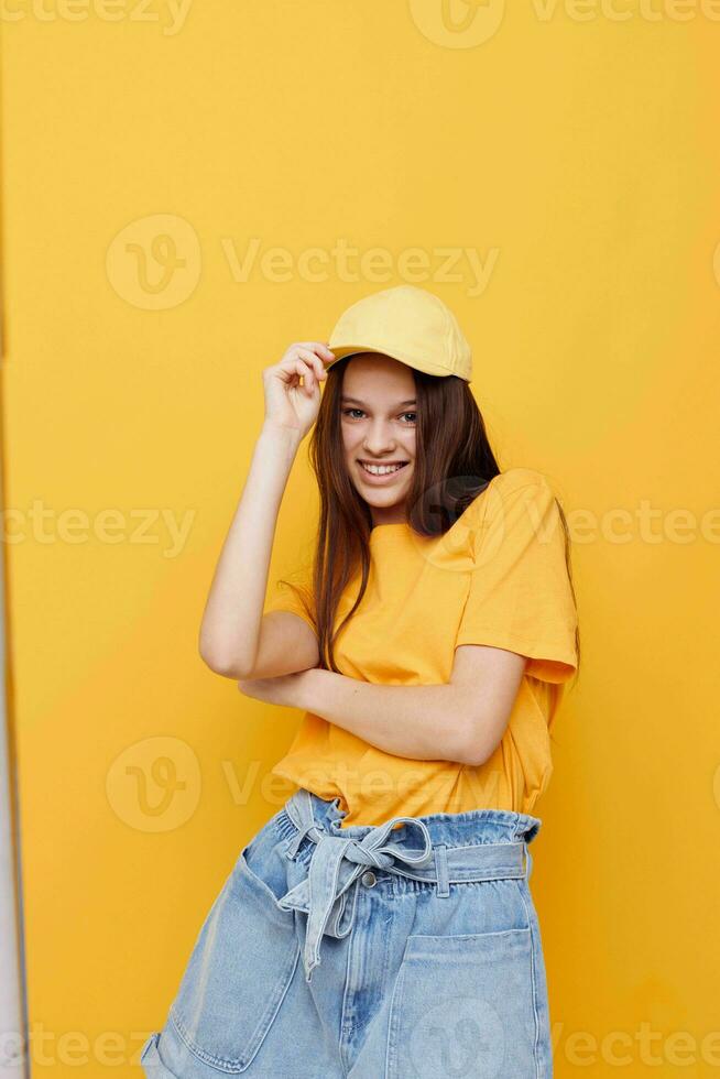 optimista joven mujer posando en un amarillo camiseta y gorra amarillo antecedentes foto