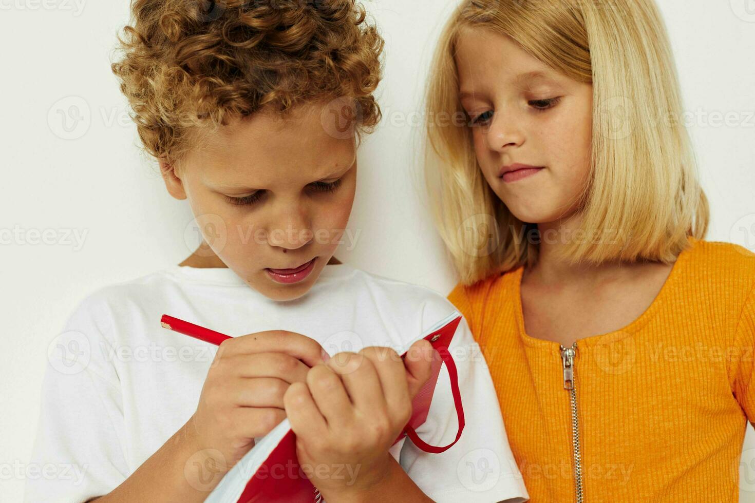 picture of positive boy and girl fun in colorful t-shirts with a notepad isolated background unaltered photo