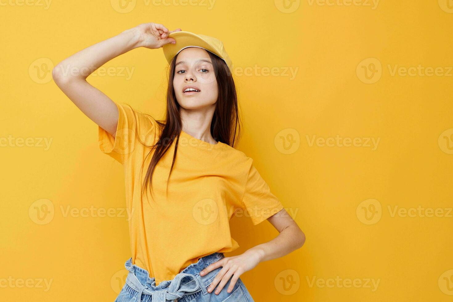 optimista joven mujer posando en un amarillo camiseta y gorra amarillo antecedentes foto
