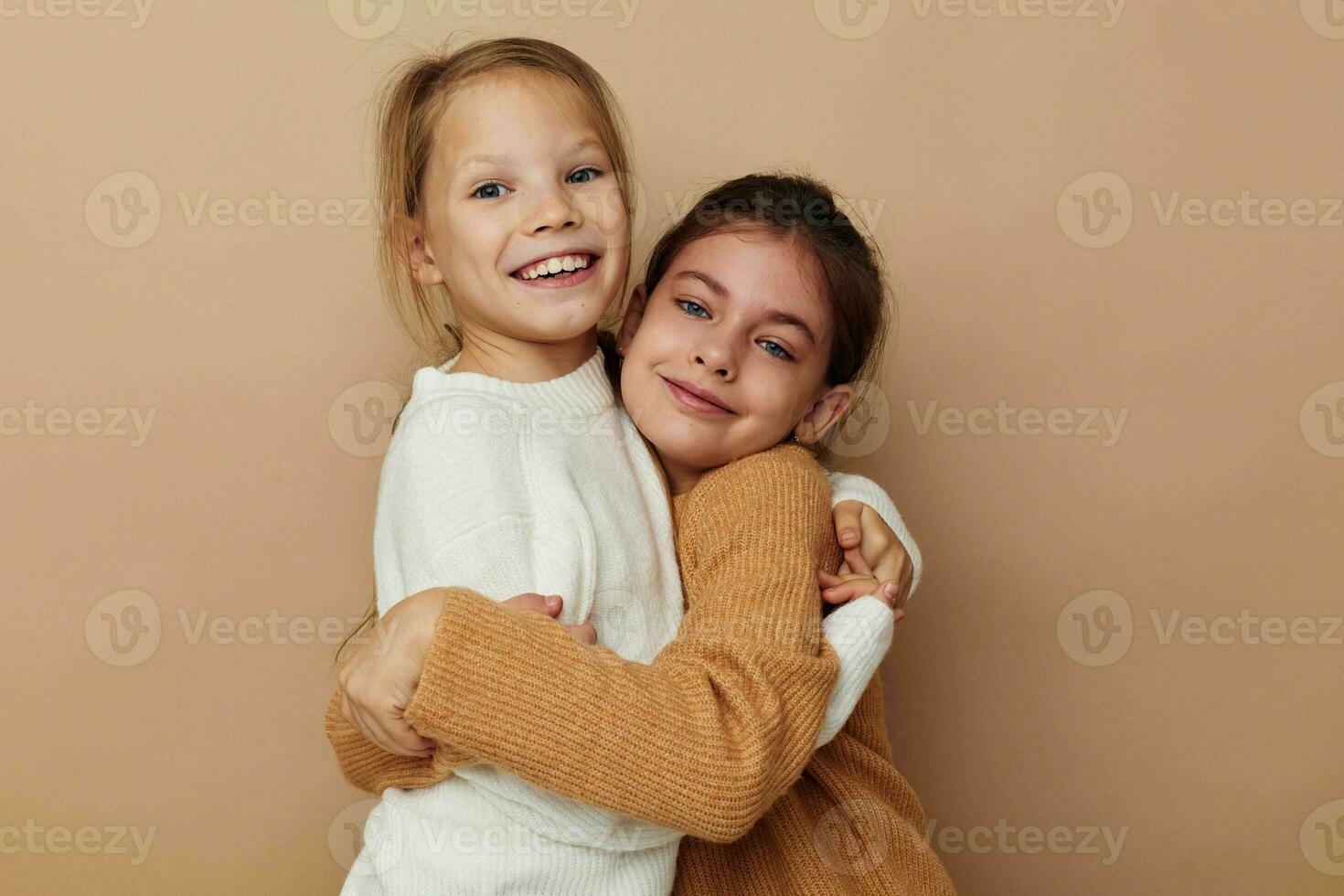 two cute little girls hug friendship beige background photo