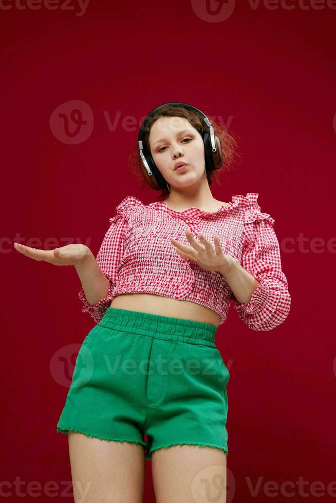 pretty woman in pink blouse and green shorts with headphones listening to music photo