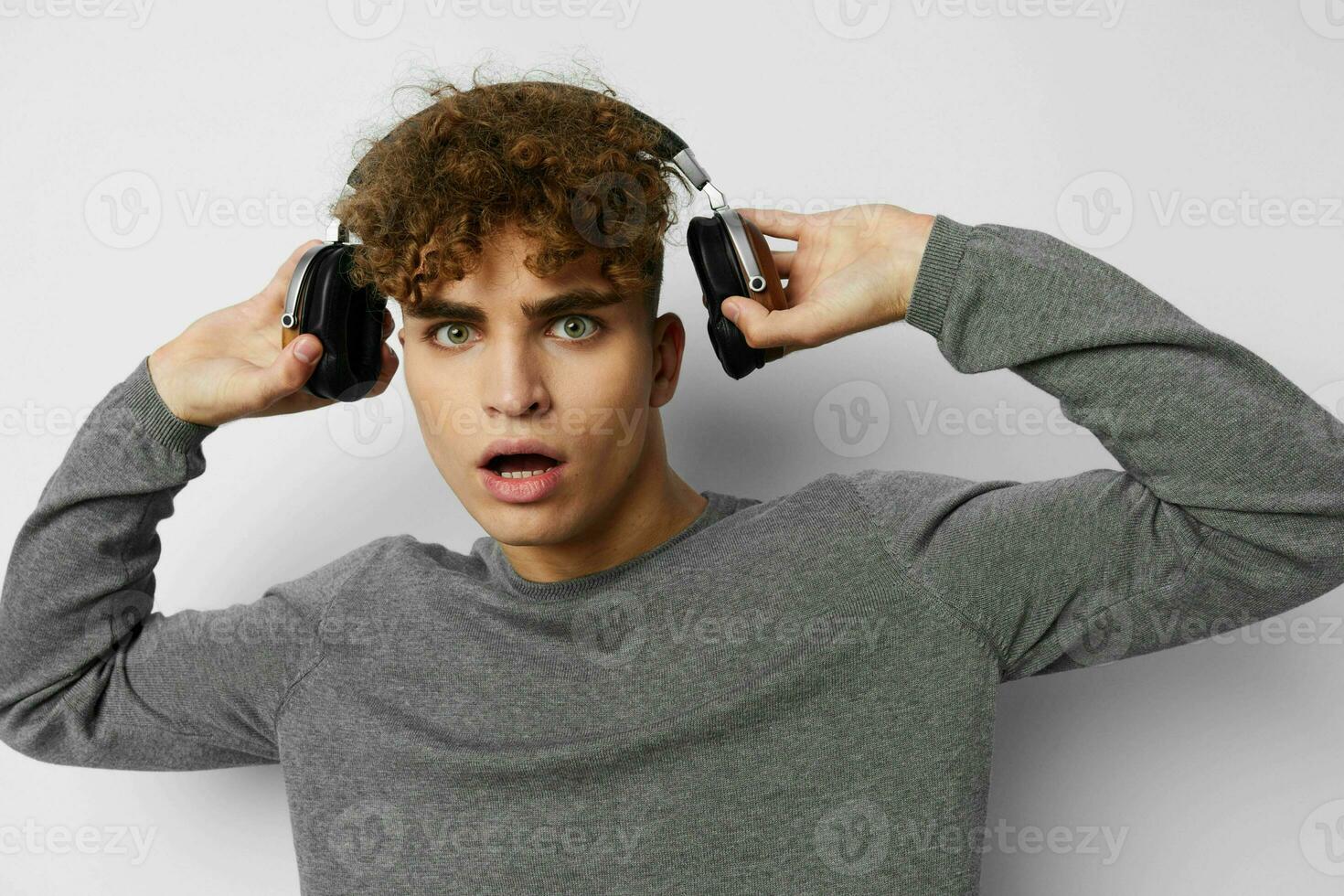 hermoso joven hombre en un gris suéter auriculares Moda ligero antecedentes foto
