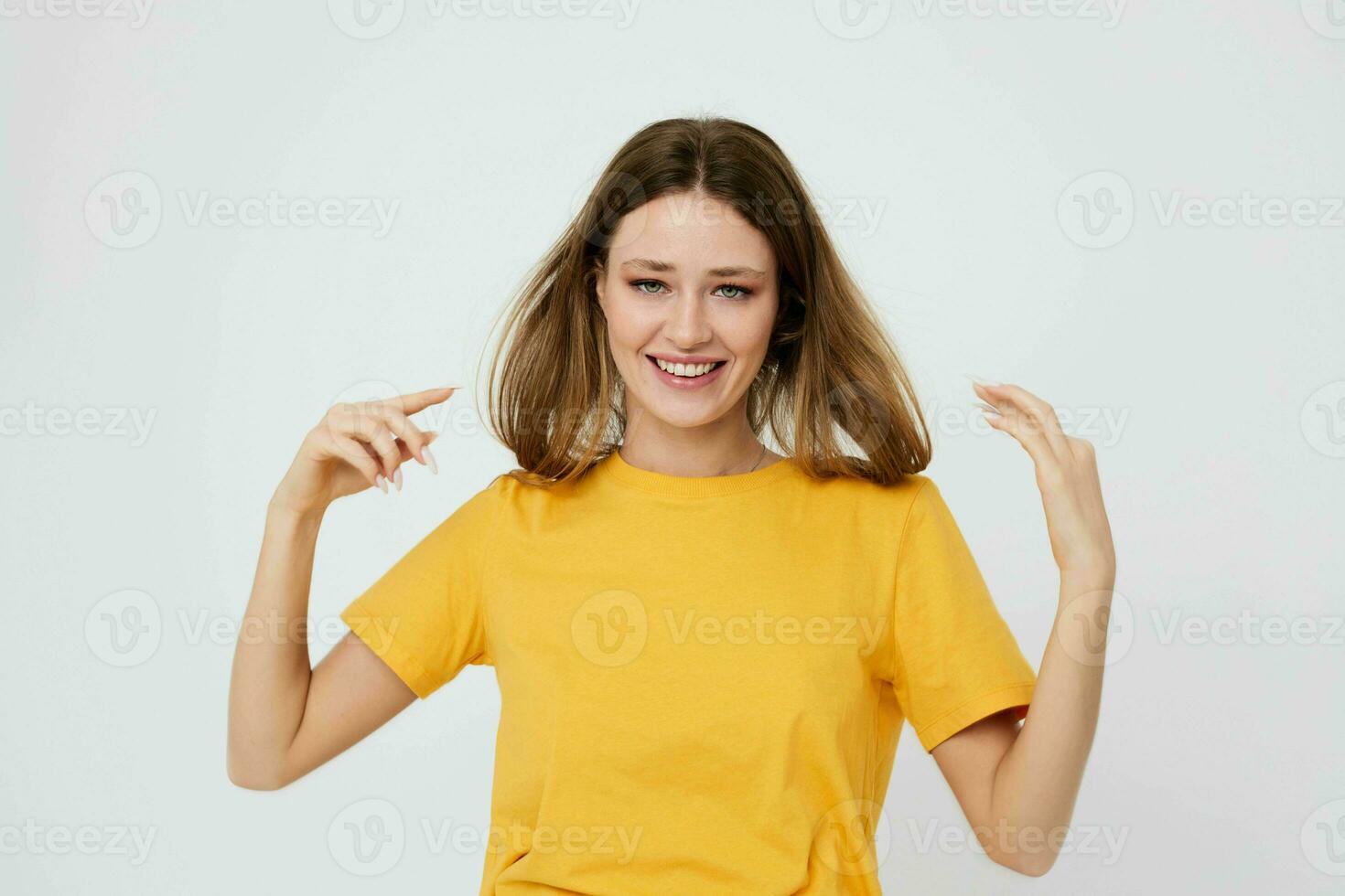 cute girl in yellow t-shirt posing hand gestures light background photo