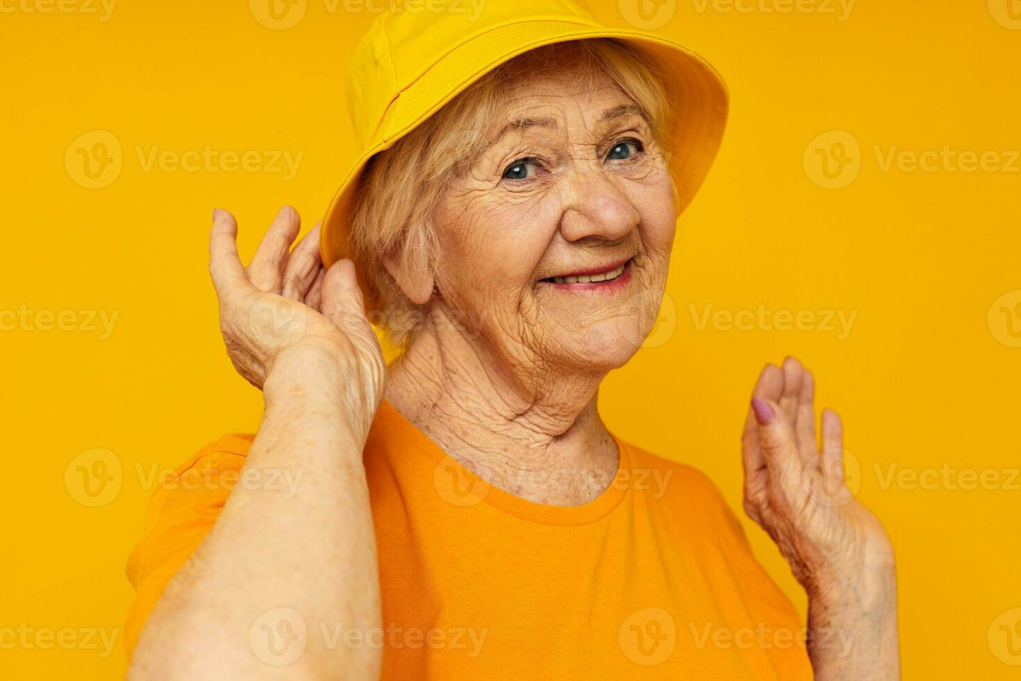 smiling elderly woman in yellow t-shirts hat posing isolated background photo