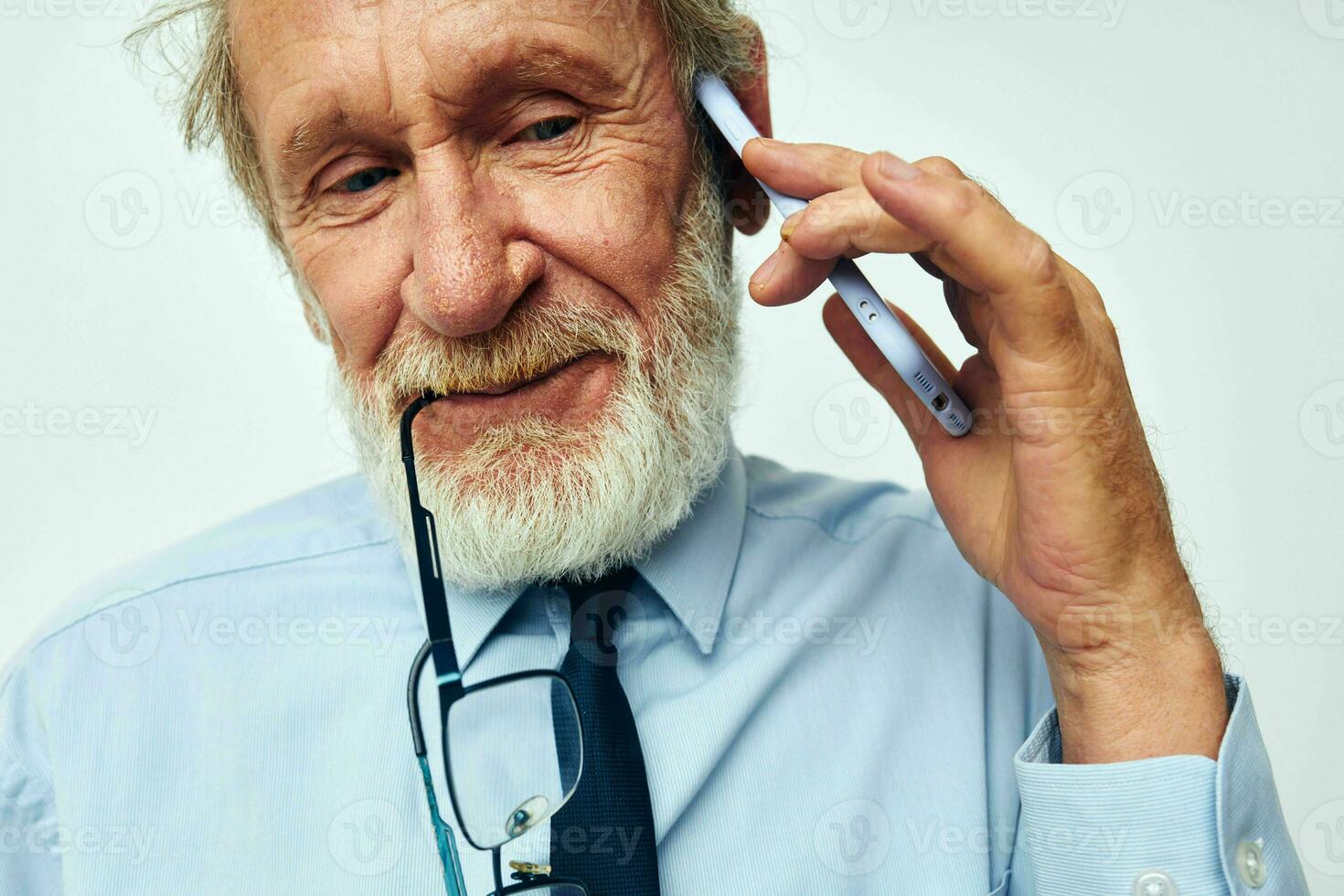 Photo of retired old man in a shirt with a tie with a phone technology light background