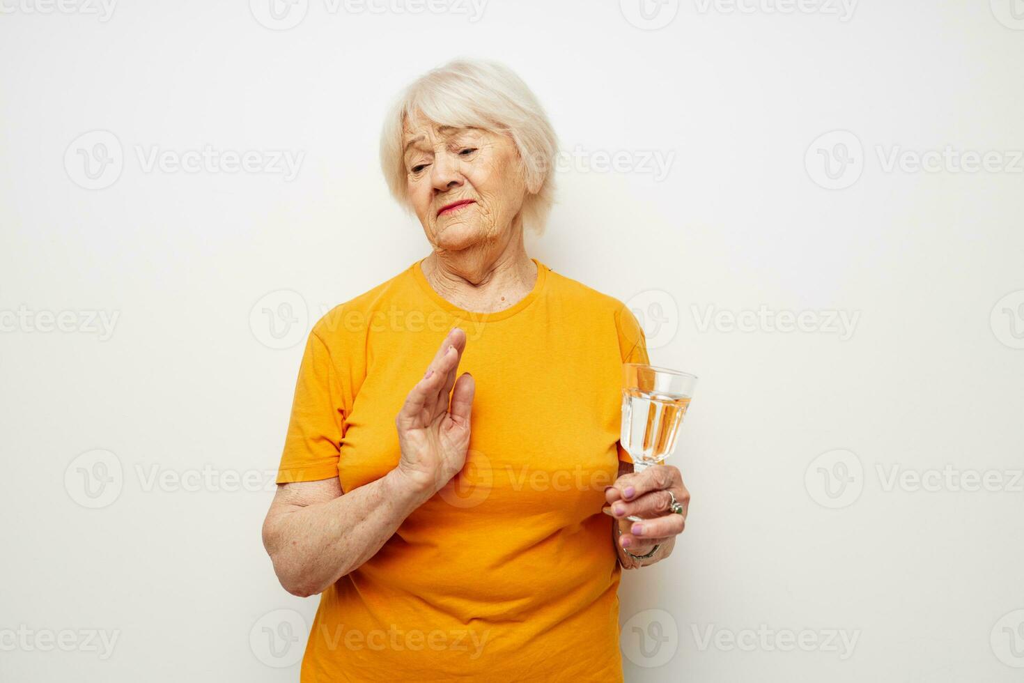 Cheerful elderly woman holding a glass of water health light background photo