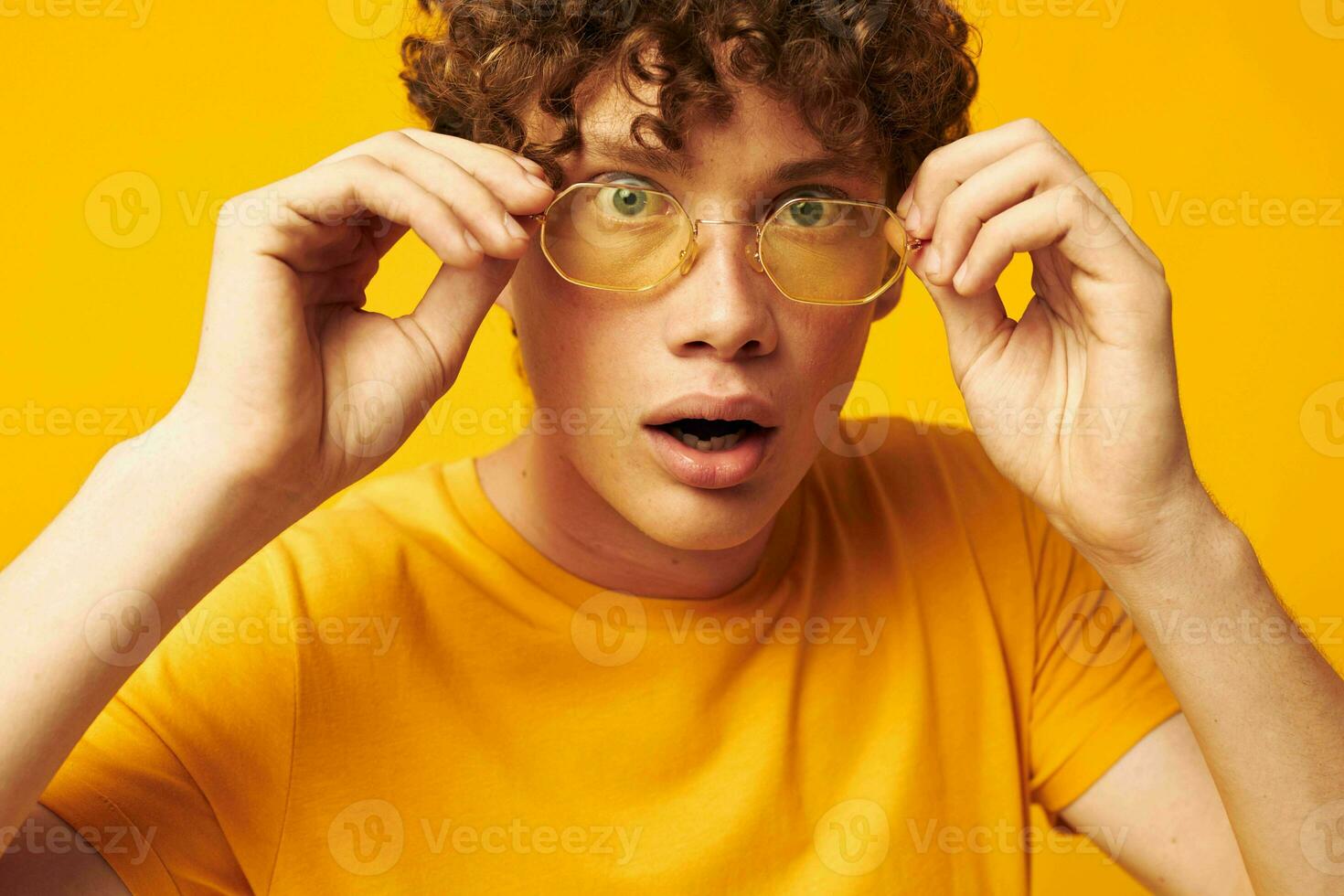 Young curly-haired man wearing stylish glasses yellow t-shirt posing monochrome shot photo