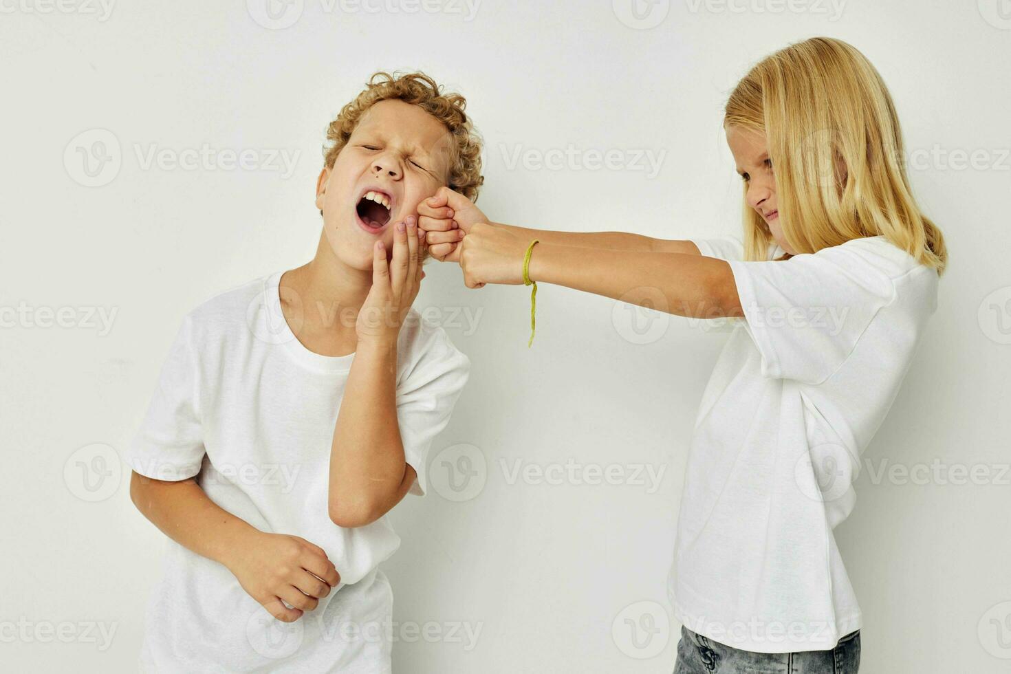 Photo of two children in white T-shirts are standing next to beige background