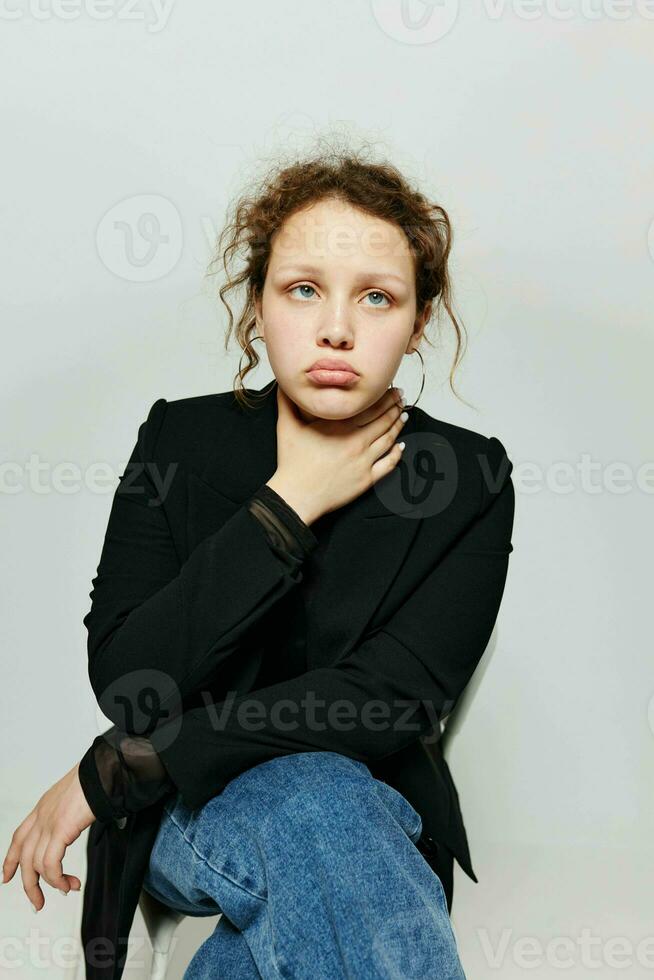 pretty woman sitting on a chair in a black jacket fashion posing light background unaltered photo