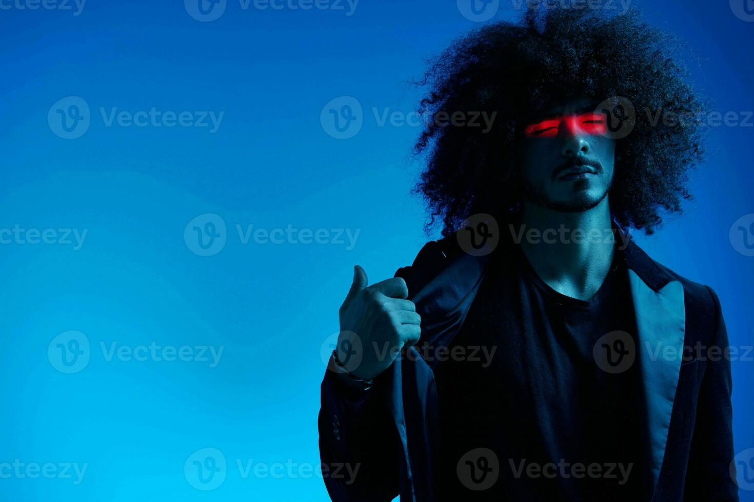 Fashion portrait of a man with curly hair on a blue background with a red stripe of light, multicolored light, trendy, modern concept. photo