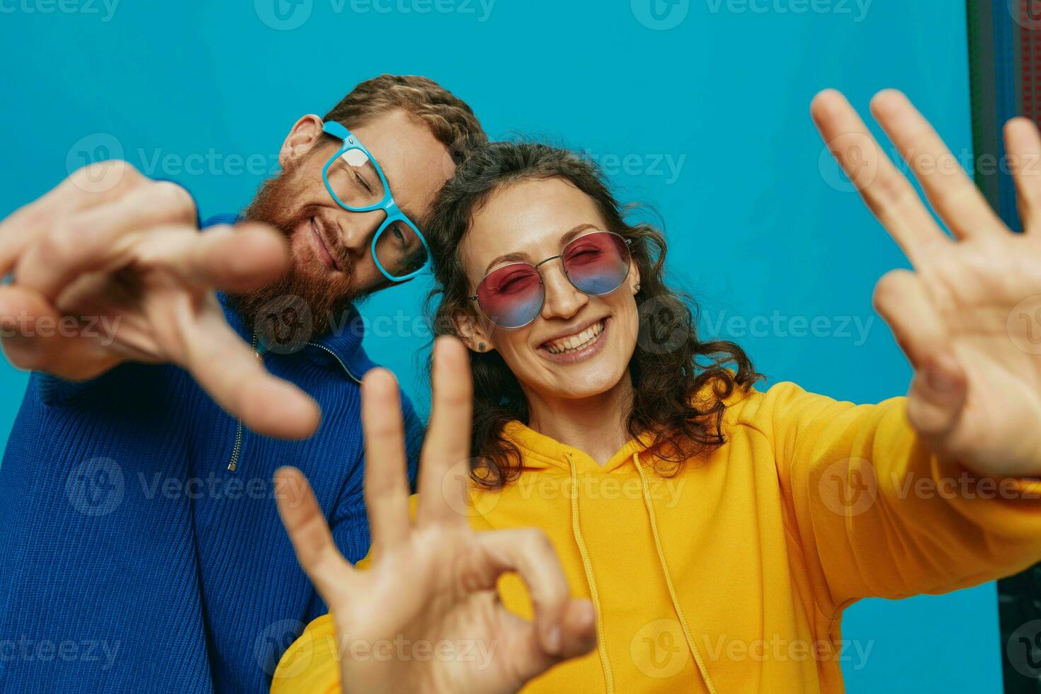 A woman and a man fun couple cranking and showing signs with their hands smiling cheerfully, on a blue background, The concept of a real relationship in a family. photo