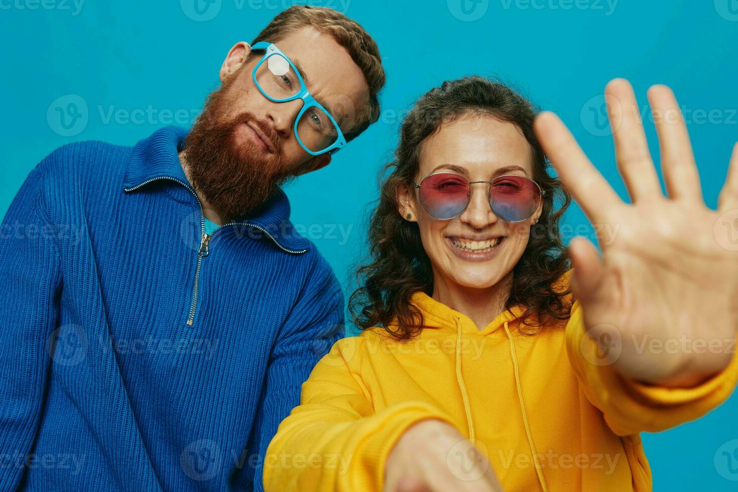 A woman and a man fun couple cranking and showing signs with their hands smiling cheerfully, on a blue background, The concept of a real relationship in a family. photo