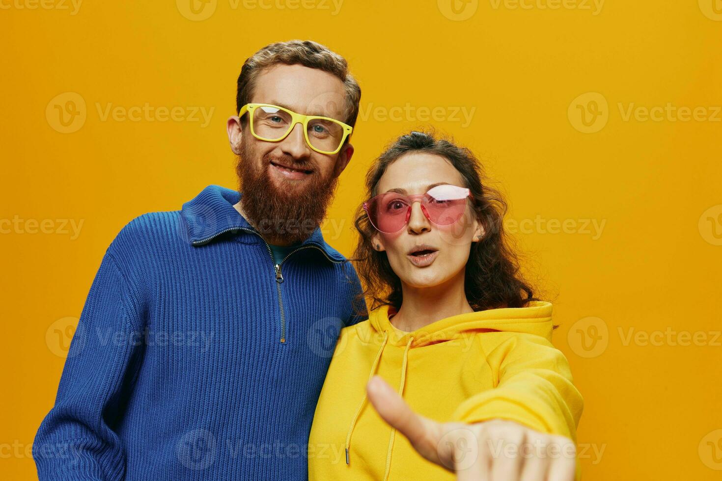 Man and woman couple smiling cheerfully and crooked with glasses, on yellow background, symbols signs and hand gestures, family shoot, newlyweds. photo