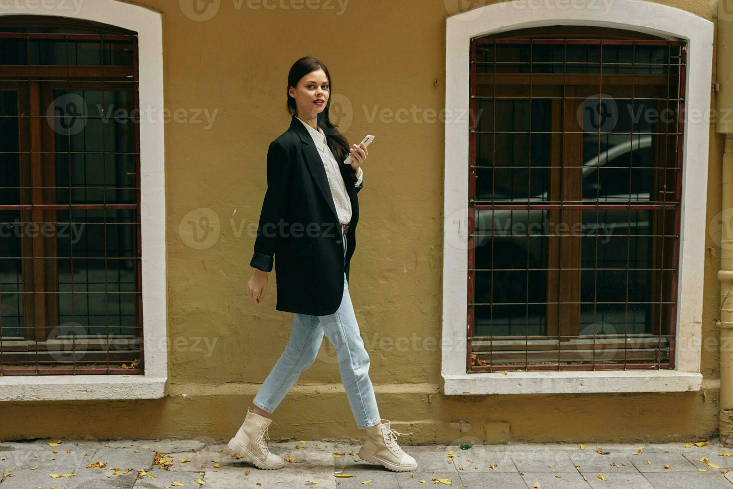 Woman blogger smile with teeth with a phone in her hands walks around the city fashion on the street, spring travel, vacation in the city tourist freelancer, mobile communication and internet for work photo