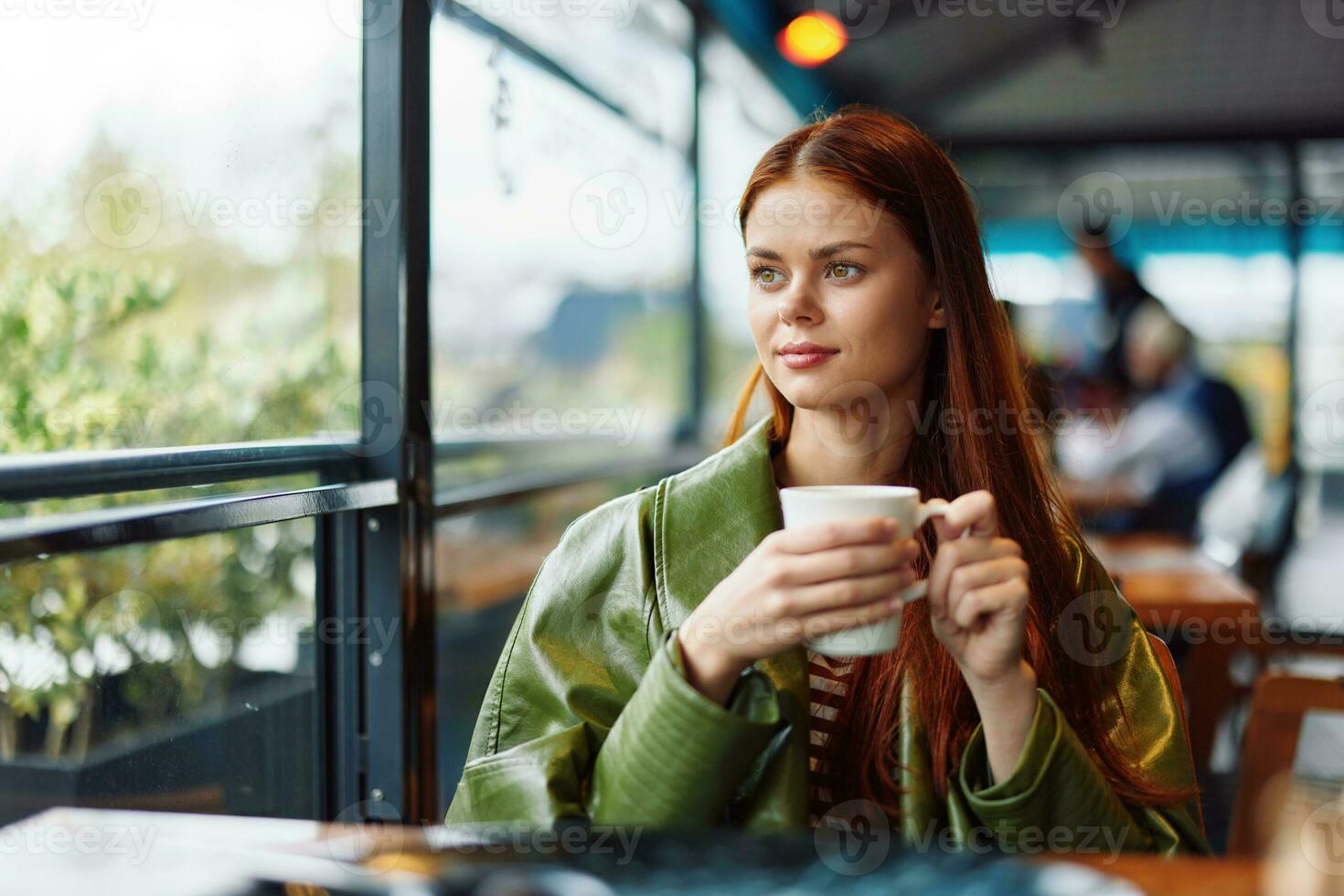 Stylish Influencer woman drinking a drink from a mug in a cafe and smiling looking out the window, content blogger photo