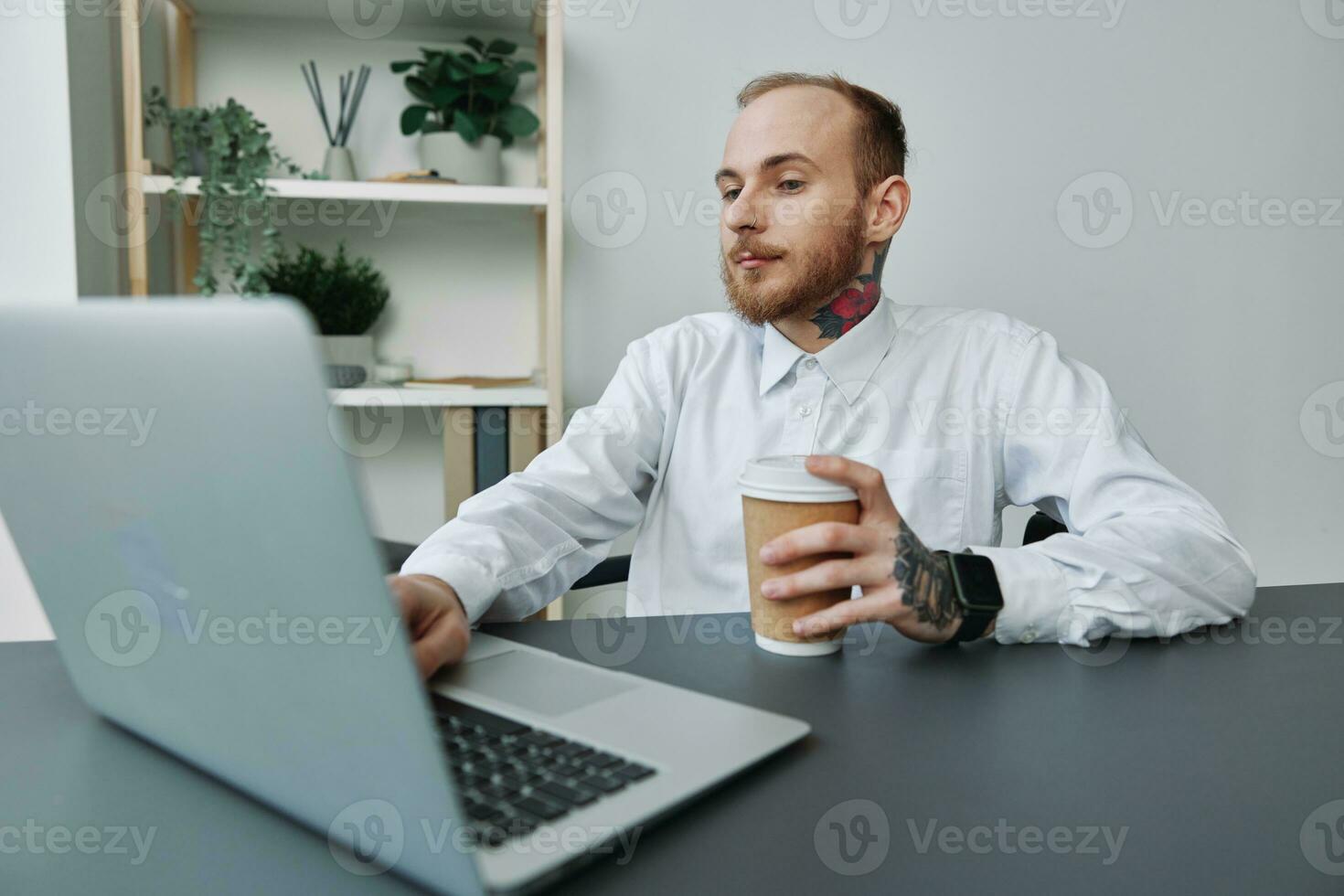 A man in a wheelchair, a businessman with tattoos in the office at a laptop, a coffee break, annoyance, the concept of working a person with disabilities, freedom from social frames photo