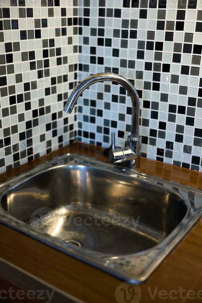 Clean sink with pouring water in the kitchen, metal faucet and sink in an old home interior. photo