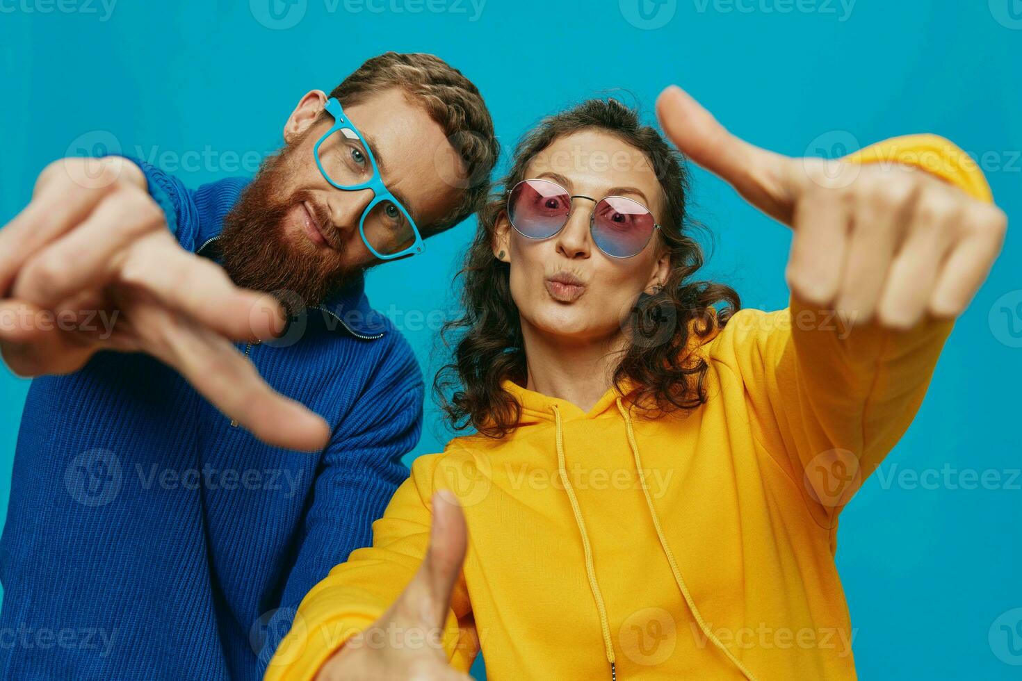 A woman and a man fun couple cranking and showing signs with their hands smiling cheerfully, on a blue background, The concept of a real relationship in a family. photo