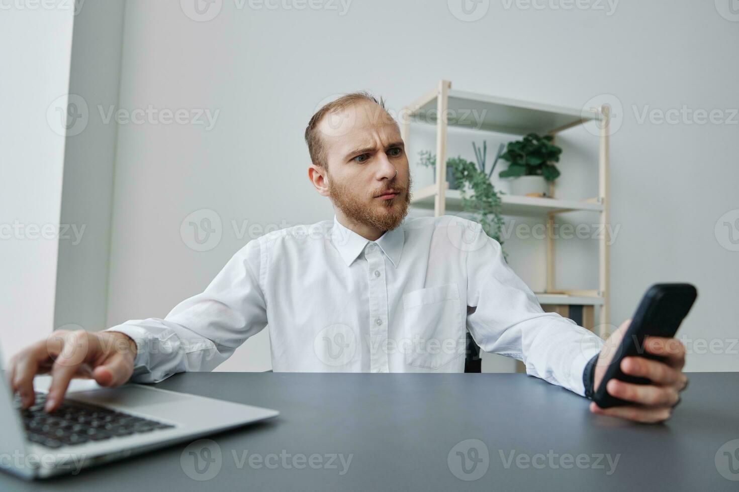 A man in a wheelchair a businessman in the office works at a laptop and holds a phone in his hands, thoughtfulness, integration into society, the concept of working a person with disabilities photo