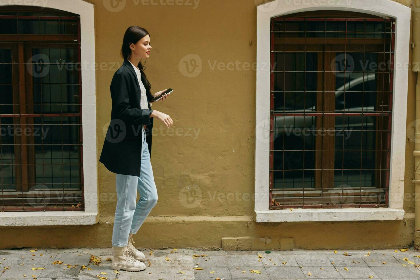 Woman blogger smile with teeth with a phone in her hands walks around the city fashion on the street, spring travel, vacation in the city tourist freelancer, mobile communication and internet for work photo