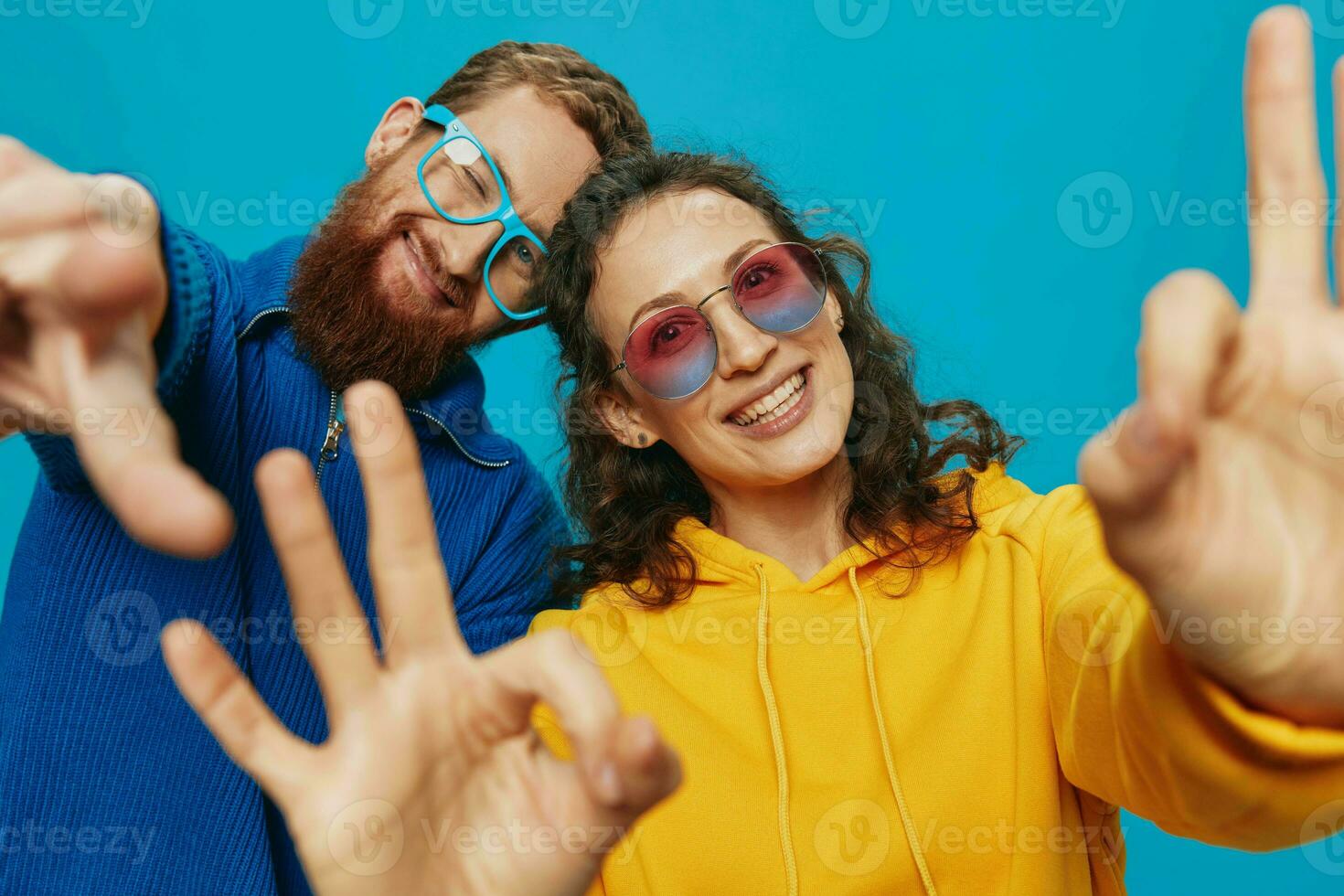 A woman and a man fun couple cranking and showing signs with their hands smiling cheerfully, on a blue background, The concept of a real relationship in a family. photo