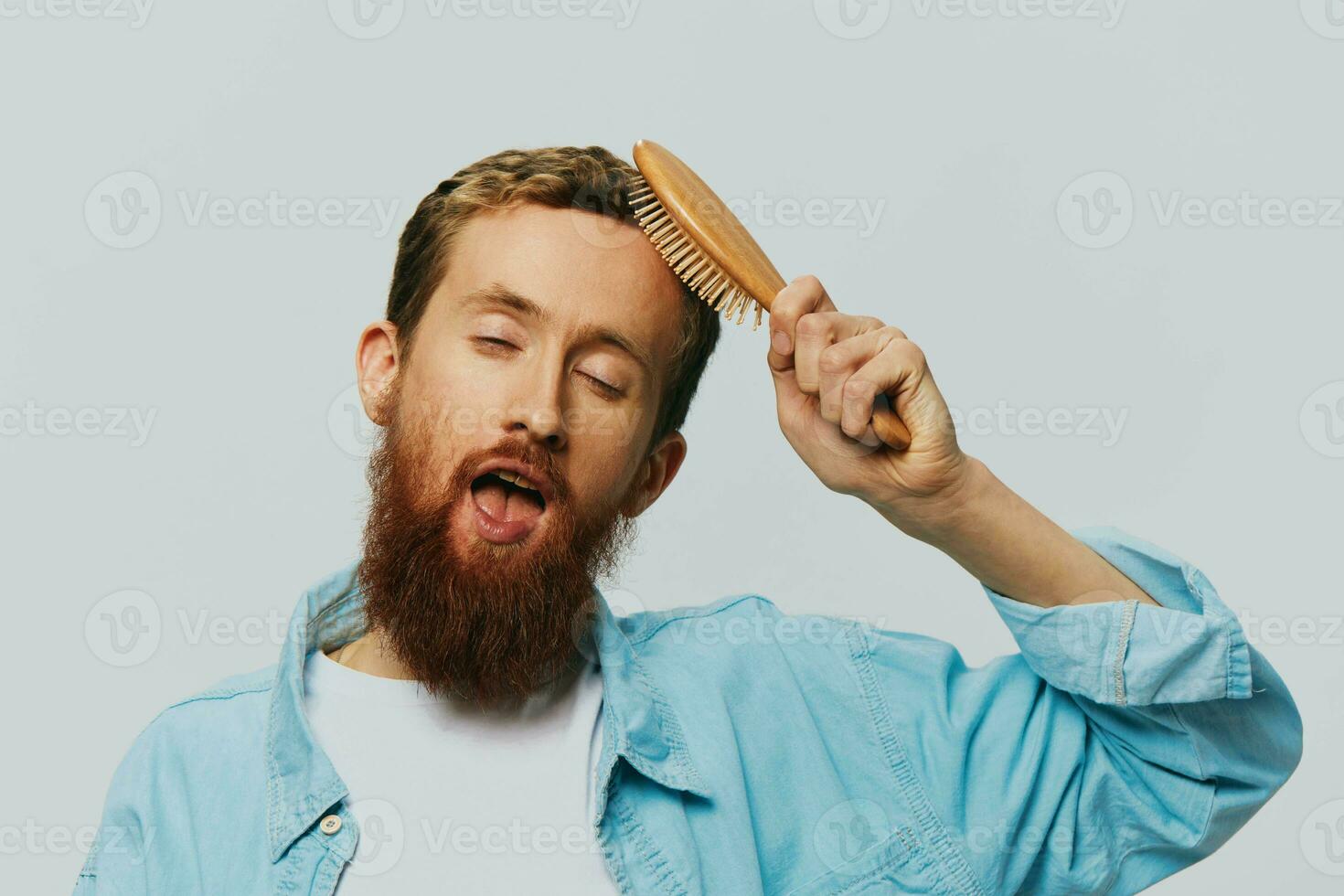 Portrait of a man with a massage comb in his hands, combing his hair and beard, hair loss problem photo